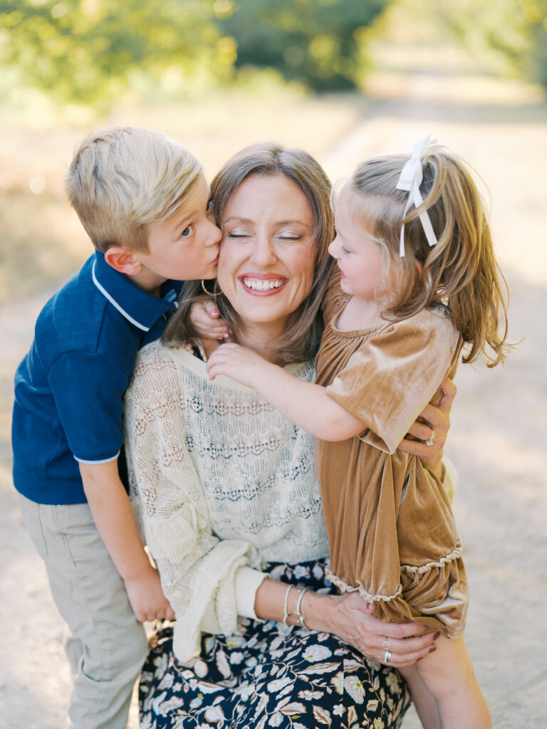 kids giving mom kissed during family photography session in dallas