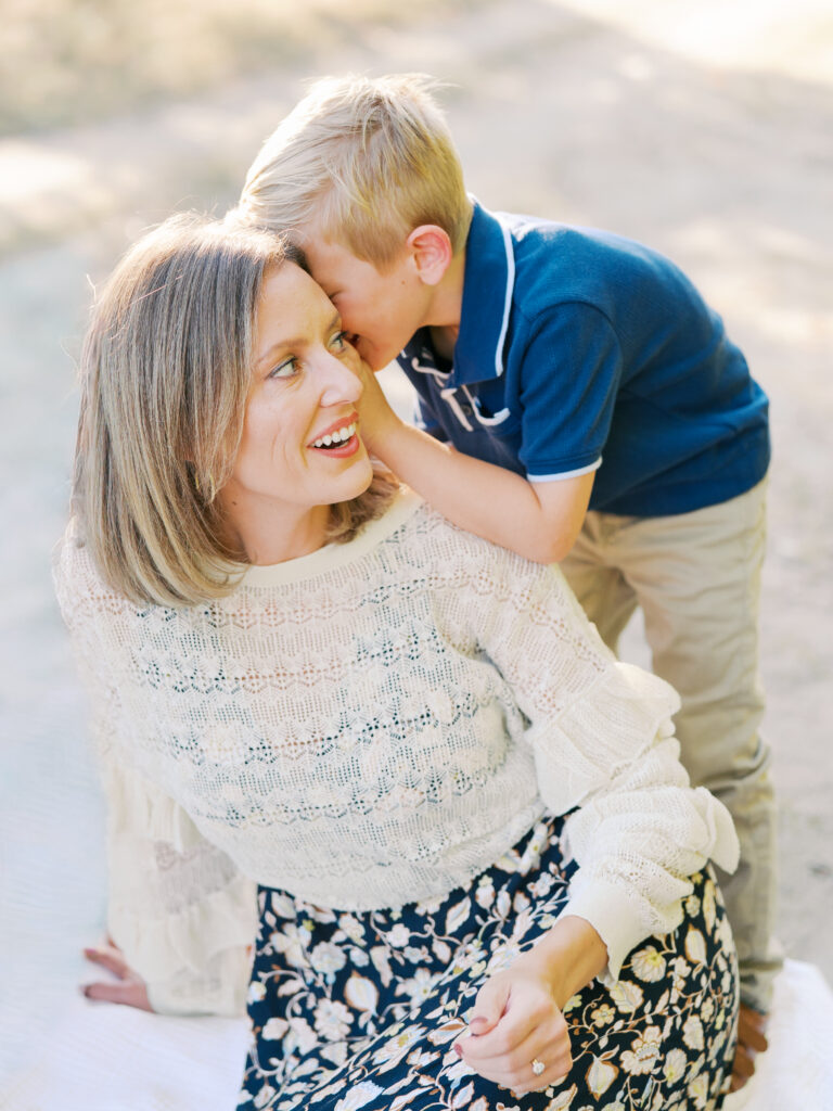 boy telling mom a secret in her ear