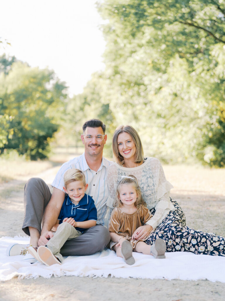 parents and children sitting in blanket and smiling