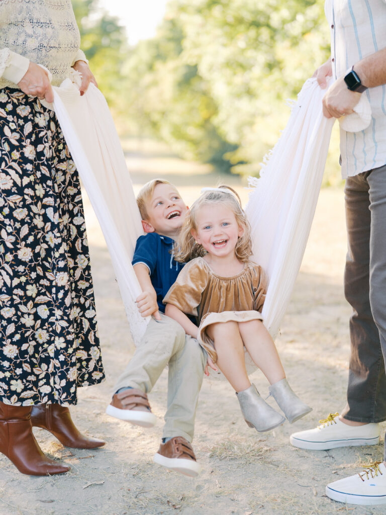 kids sitting in picnic blanket and laughing during their spring family session in dallas